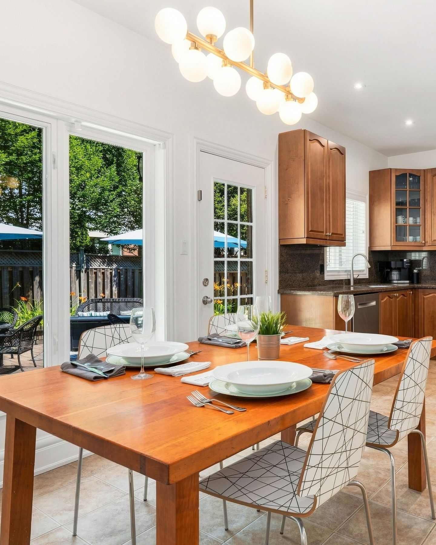 Bright dining area with globe chandelier, set table and patio doors