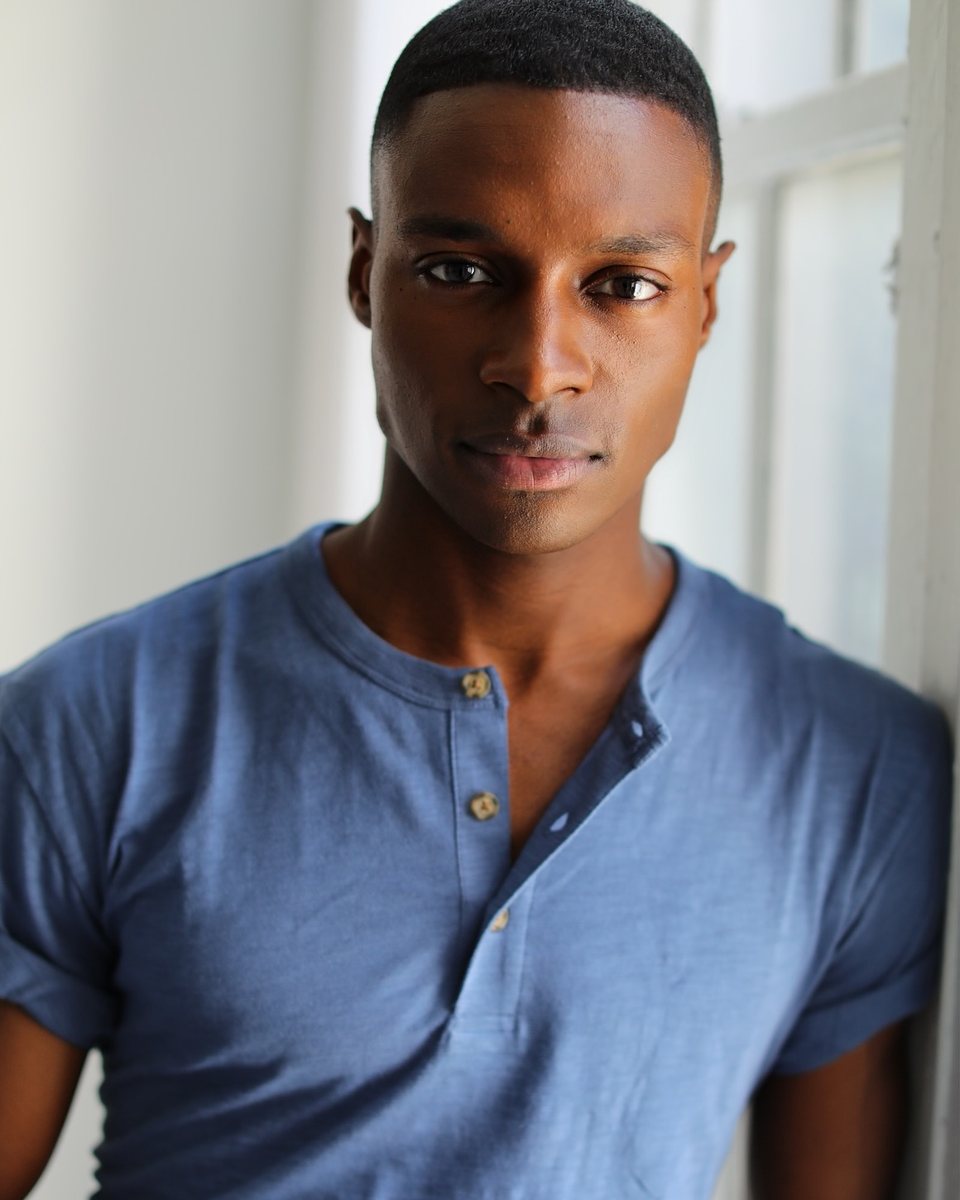 Man in a blue henley leaning by a bright window